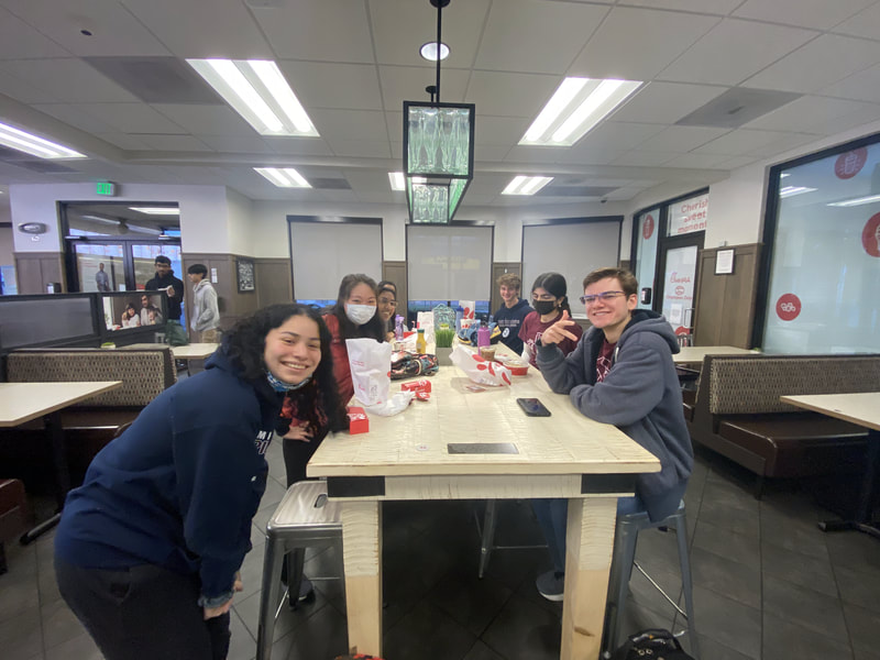 A group of students sit smiling at a table in Chick-fil-A.